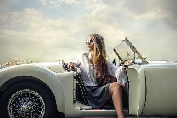 Fille à lunettes posant sur fond de voiture blanche