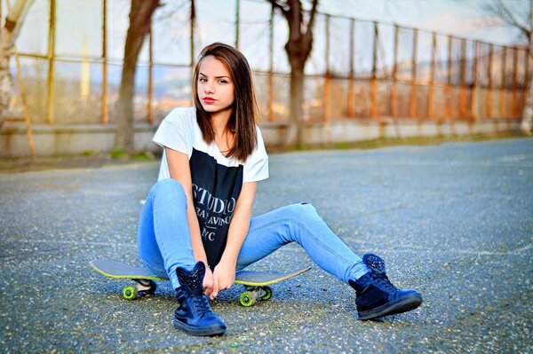 A girl in Bulgaria is sitting on a skateboard