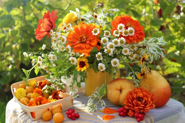 Sul tavolo in giardino un mazzo di dalie e nivyanik, frutta e bacche in un cestino