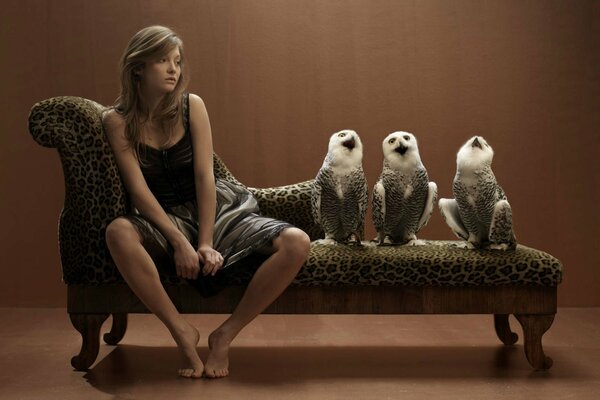 A girl is sitting on a sofa with owls