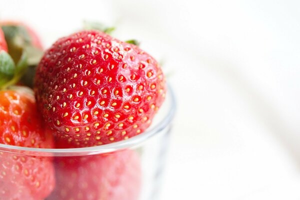 Juicy mature strawberries in a transparent bowl