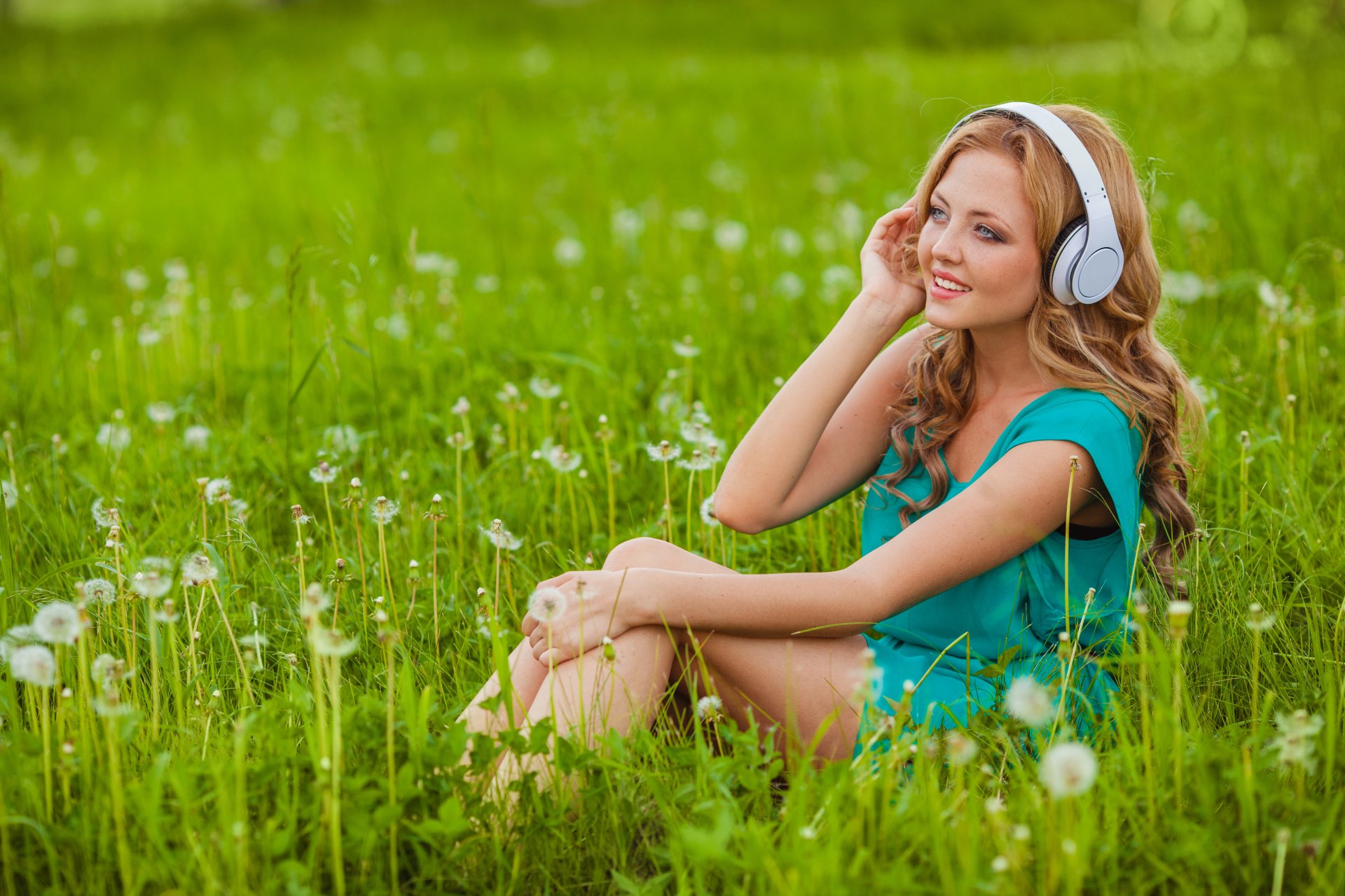 chica rubia hierba dientes de león flores auriculares sonrisa