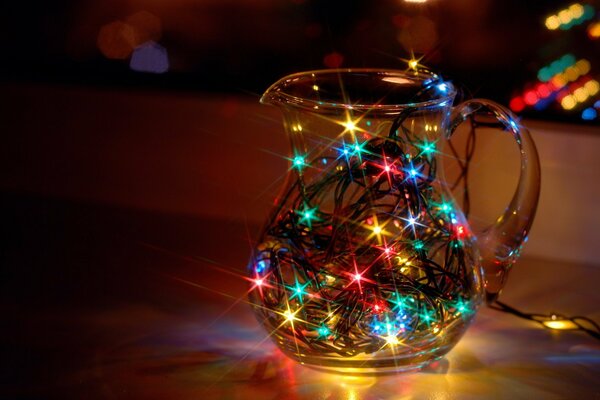 Multicolored lights of a garland glow in a glass jug