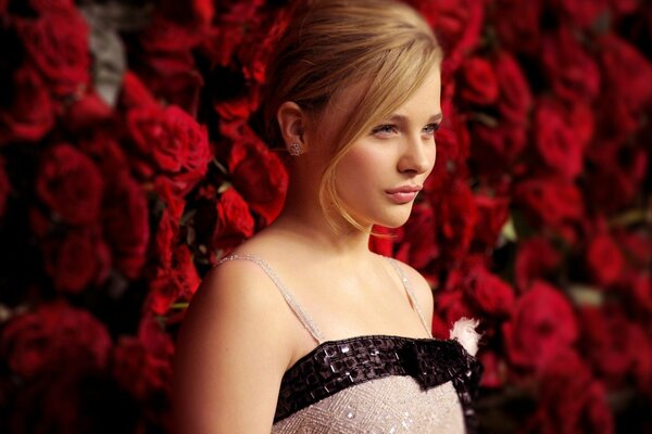 Chloe Grace Moretz against a wall of red roses