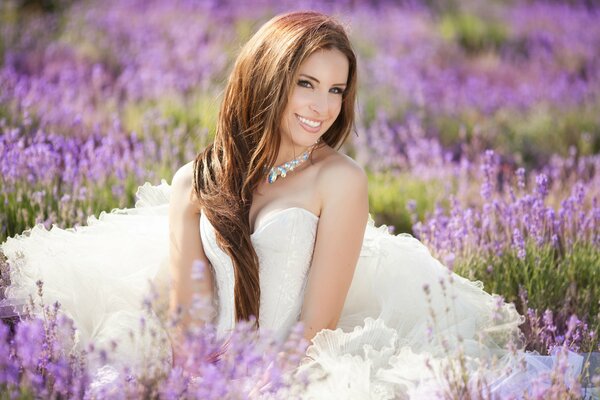 Una chica con un vestido blanco se sienta en un campo de lavanda