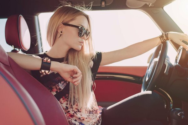 Blonde Mädchen sitzt hinter dem Steuer eines Autos