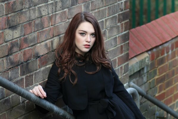 Brunette en manteau noir sur les escaliers