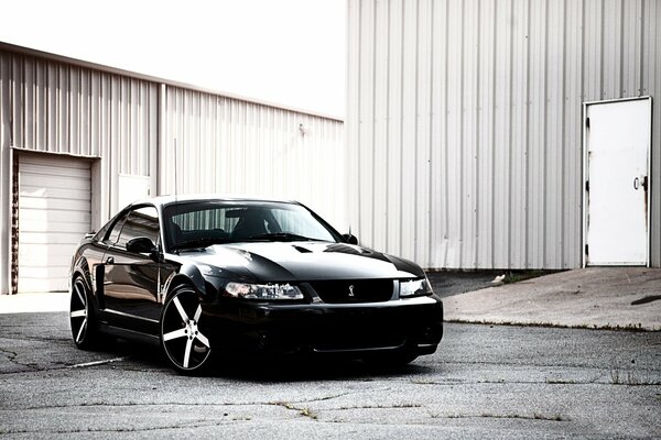 The black Mustang is parked in the hangar