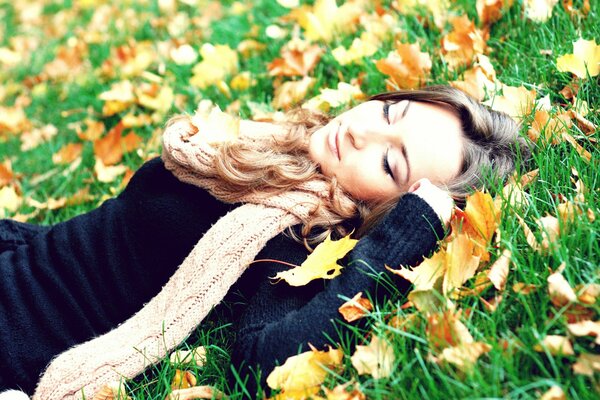 The girl lies in the leaves and grass, autumn photo