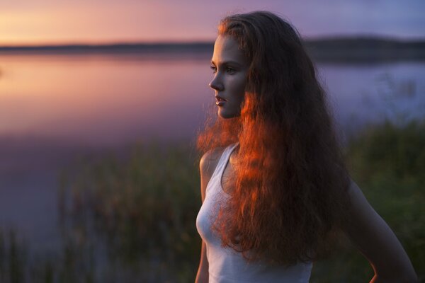 Fille aux cheveux rouges près du lac du soir