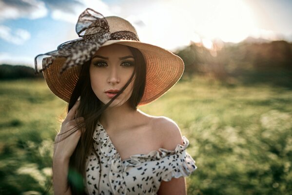 A girl with long hair and a hat in a meadow