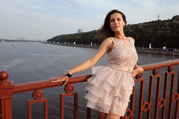 Chica en vestido rosa posando en el puente