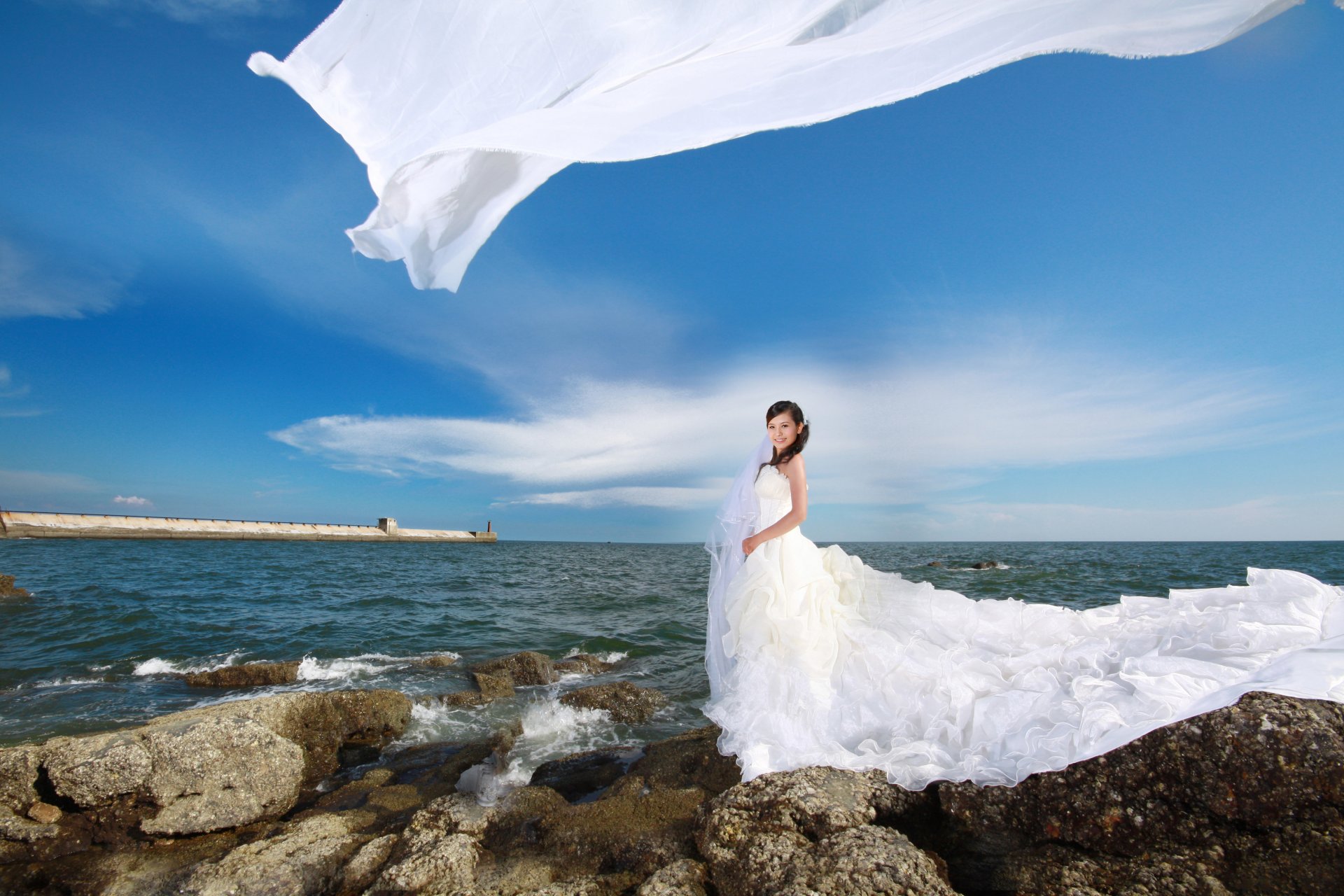 mädchen asiatisch hochzeitskleid weiß steine meer wellen himmel wolken