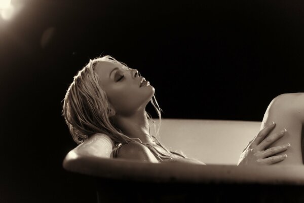 Schönes Mädchen in der Badewanne auf schwarzem Hintergrund