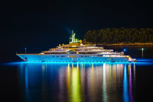 Luksusowy jacht płynie obok wyspy w nocy