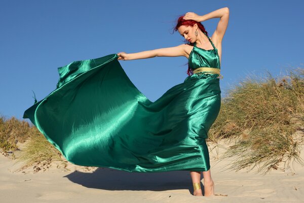 Dziewczyna pozuje na piasku. Zielona sukienka tren