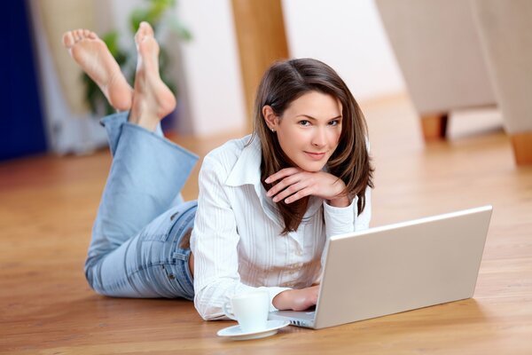 The look of a brown-eyed brown-haired woman lying on the floor near a laptop