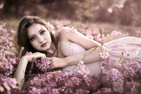 Belle fille se trouve dans des fleurs serein