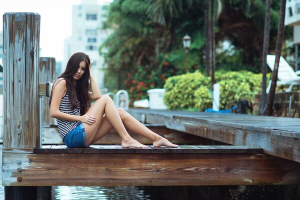 Mädchen in Shorts sitzt am Fluss