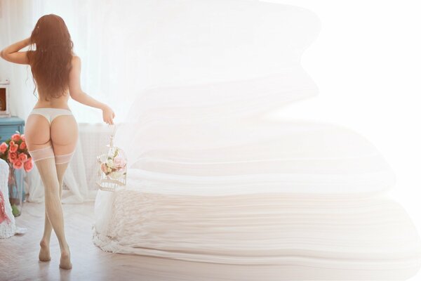 A girl in stockings with long legs, a beautiful ass and panties, holding a bouquet of flowers in her hands