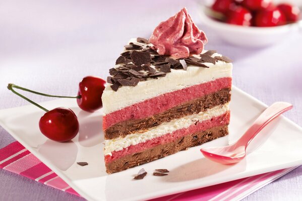 Striped sponge cake on a square plate decorated with cherries