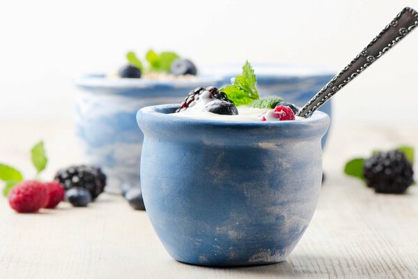 A cup of yogurt with raspberries and blueberries on the table