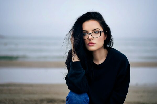 Mädchen mit Brille ist traurig vor dem Hintergrund des Wassers