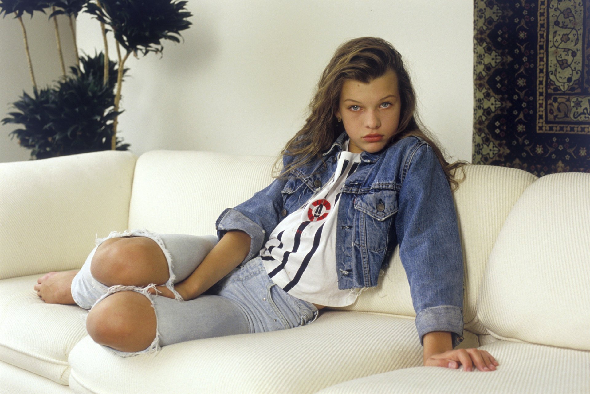 berühmt schauspielerin mila jovovich jung mädchen mila hoffnungsvoll ermutigend mila jovovich model jovovich aussehen aussteigen hollywood kunst film film kind brünette schönheit lange haare augen jeans weste jacke sofa pose