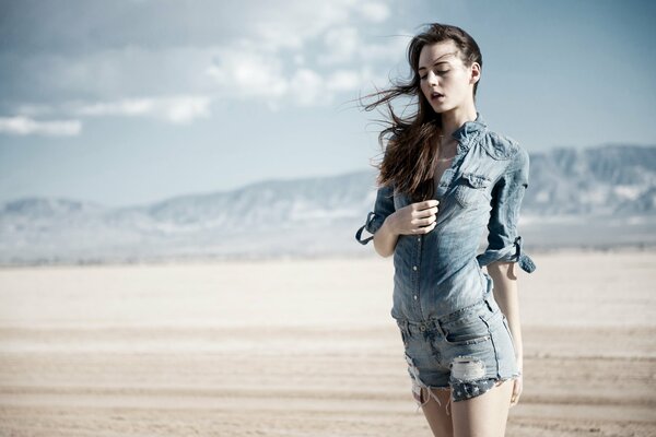 The girl s hair is fluttering in the wind in the desert