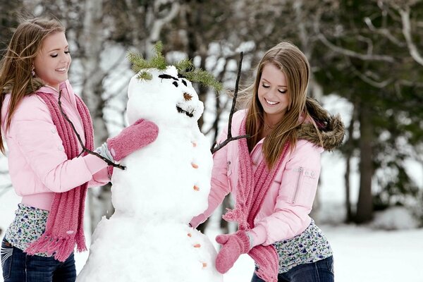 Zwillinge in Fäustlingen formen einen Schneemann