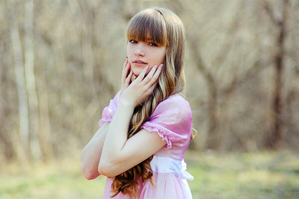 A girl in a pink dress in the middle of the forest