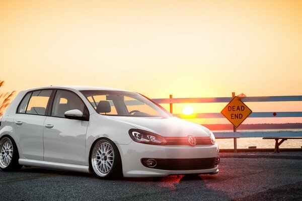 White car at the fence at sunset