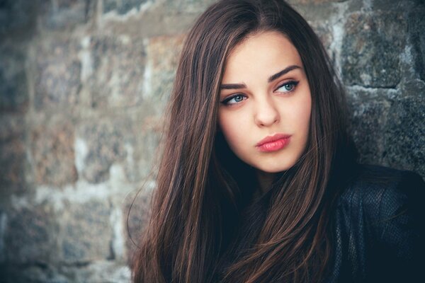 Bruna con gli occhi azzurri distoglie lo sguardo da parte contro il muro