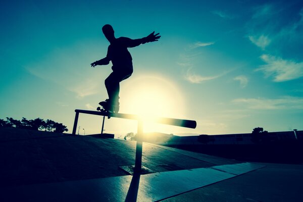 Skateboarder performs tricks against the background of the sun