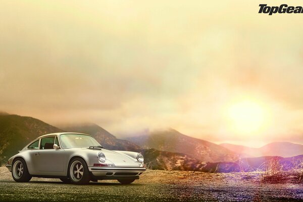 Ein grauer Porsche steht vor dem Hintergrund des Sonnenuntergangs
