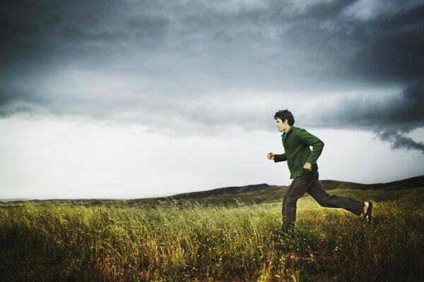 Un homme court sur un champ par temps nuageux