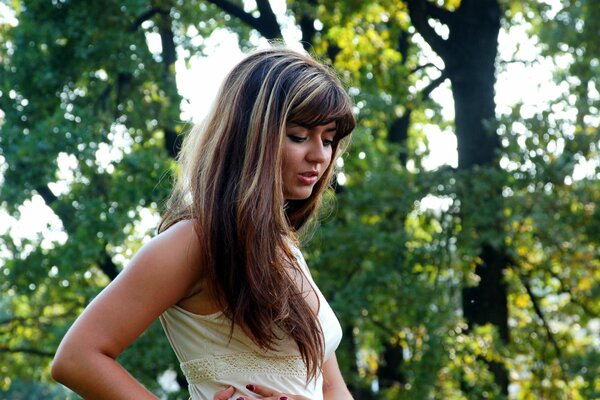 A girl with long hair against the background of trees in the forest