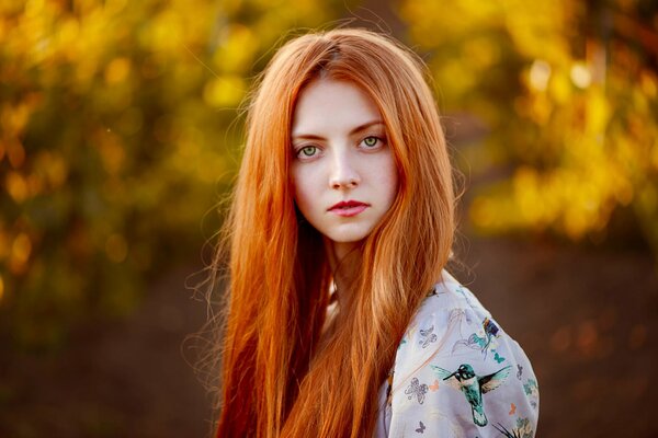 Autumn portrait of a red-haired girl with a blurred background