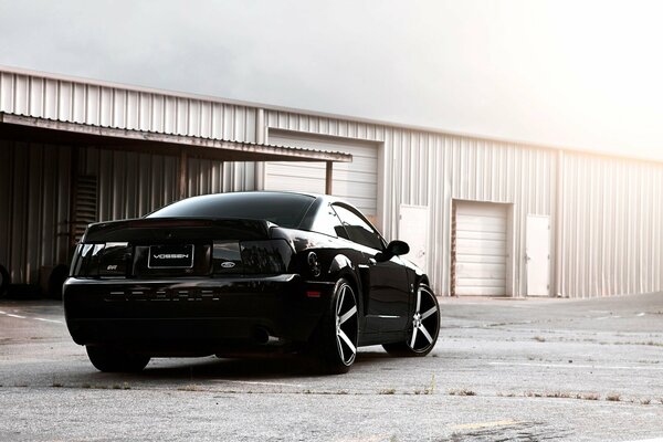 Black Ford Mustang on the background of a hangar