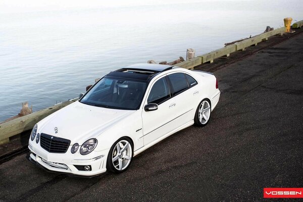 Mercedes bianca sulla strada vicino al mare