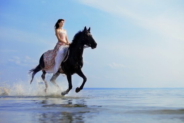 Braunhaarige Frau reitet auf einem Pferd auf dem Meer