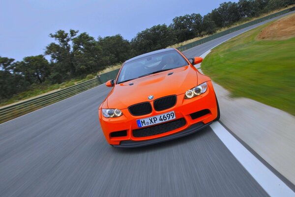 Pomarańczowe BMW jeździ po drodze