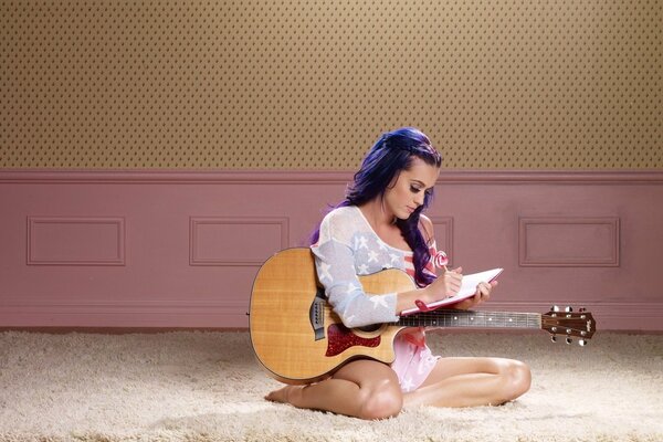 Katy Perry compose de la musique avec une guitare