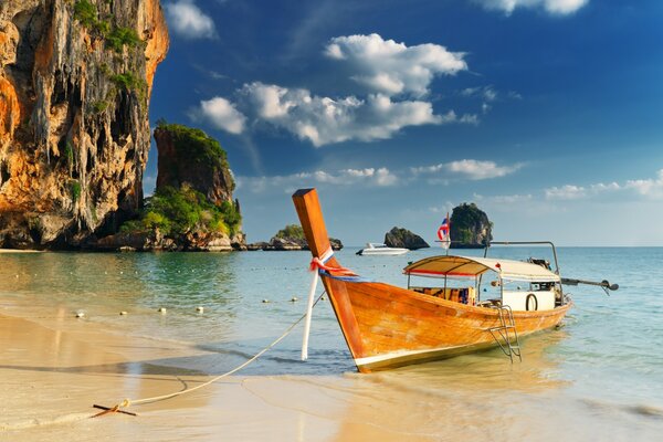 BOAT ON THE SHORE AT THE FOOT OF THE CLIFF