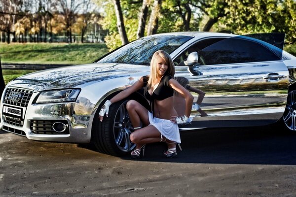 A silver car with a girl next to it