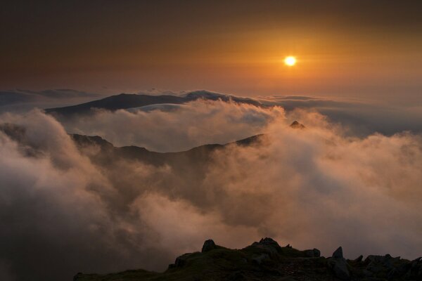 El sol Poniente sobre las montañas y la niebla