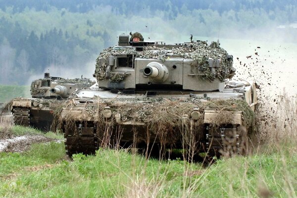 Carro armato travestito con soldati cavalca sullo sfondo della foresta