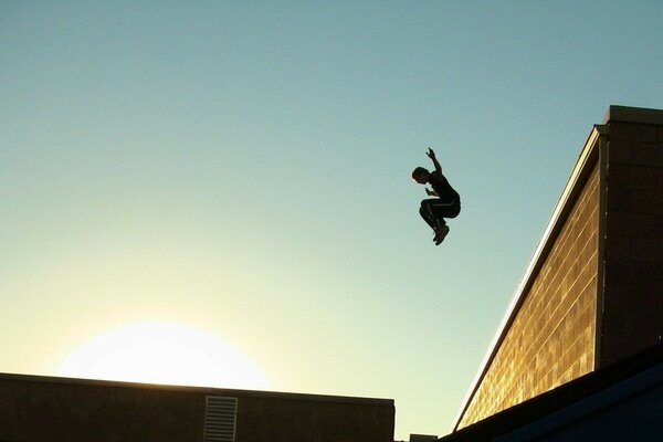 Uomo che salta dal tetto nei raggi del sole