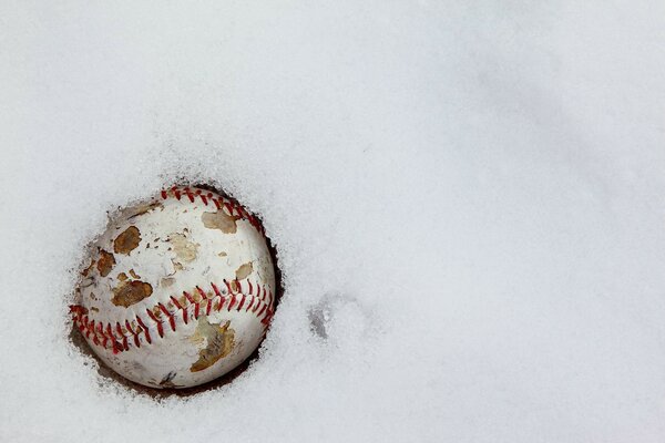 A cracked old baseball in the snow