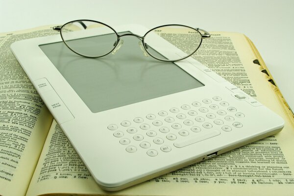 The glasses are on an electronic and regular book